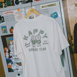 White t-shirt with graphic design and text hanging on a wooden hanger against a refrigerator background.